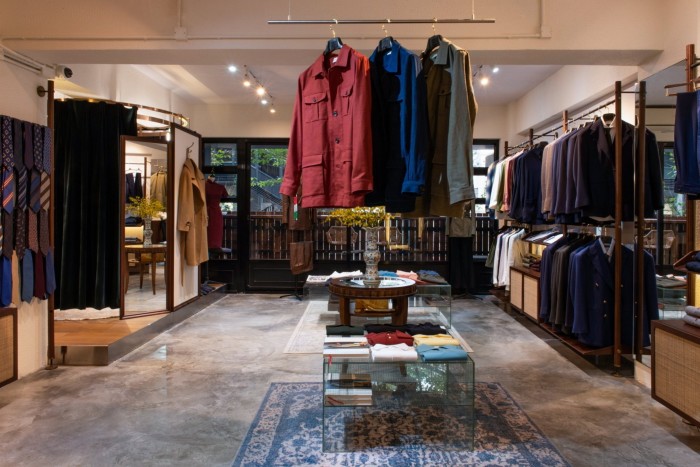 The showroom at Hong Kong tailor Prologue, with red, blue and grey jackets dangling from a brass rod hanging below the ceiling