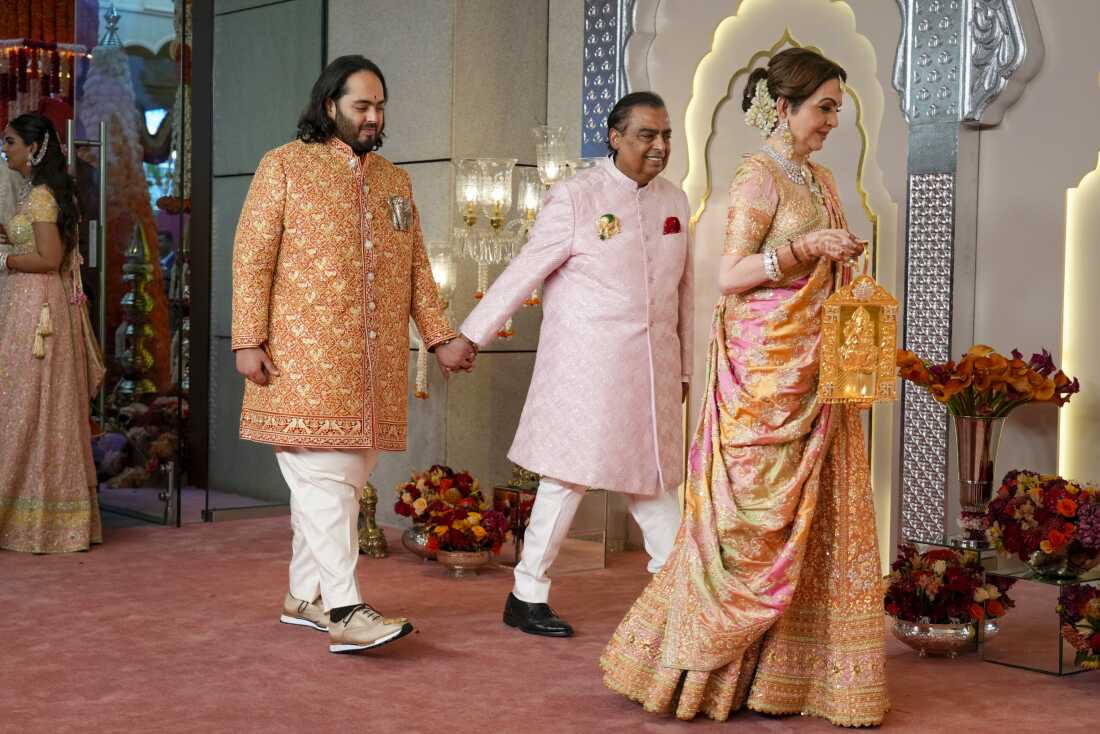 Billionaire Mukesh Ambani, center, takes his son Anant Ambani by the hand as they walk with Nita Ambani, right, at the wedding of Anant and Radhika Merchant at Jio World Convention Centre in Mumbai, India, Friday, July 12, 2024. (AP Photo /Rajanish Kakade)