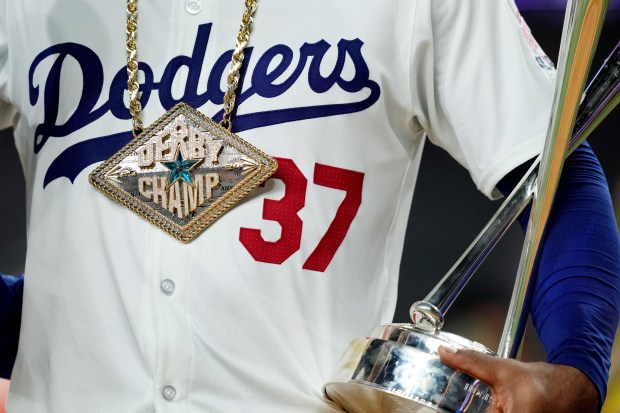 Dodgers outfielder Teoscar Hernández holds the trophy and wears the...