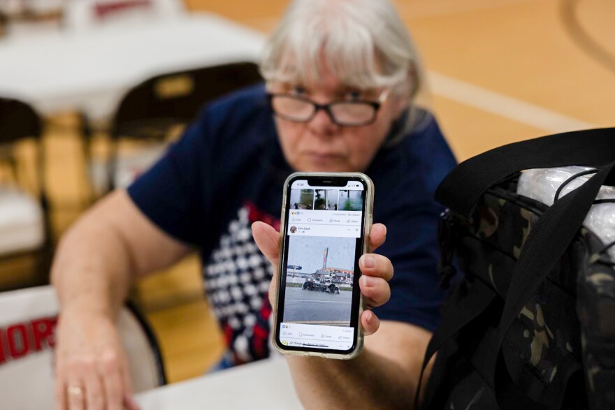 Diane Kurwicki of Nashville, Ill. holds up her phone showing flooding near her home while sheltering at Trinity Lutheran Church on July 12, 2024.