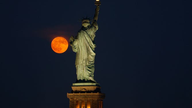 through a haze behind the Statue of Liberty in New York City on July 2, 2023, as seen from Jersey City, New Jersey.