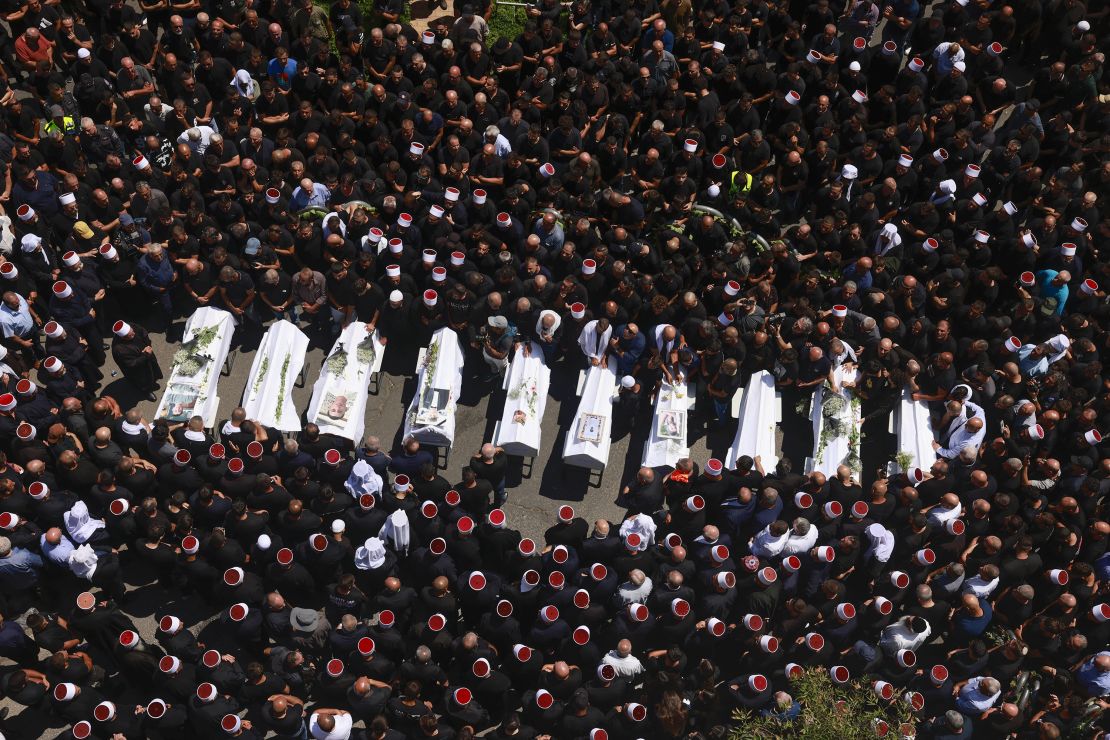 Druze elders and mourners surround the coffins of 10 of the children killed in Saturday's strike.