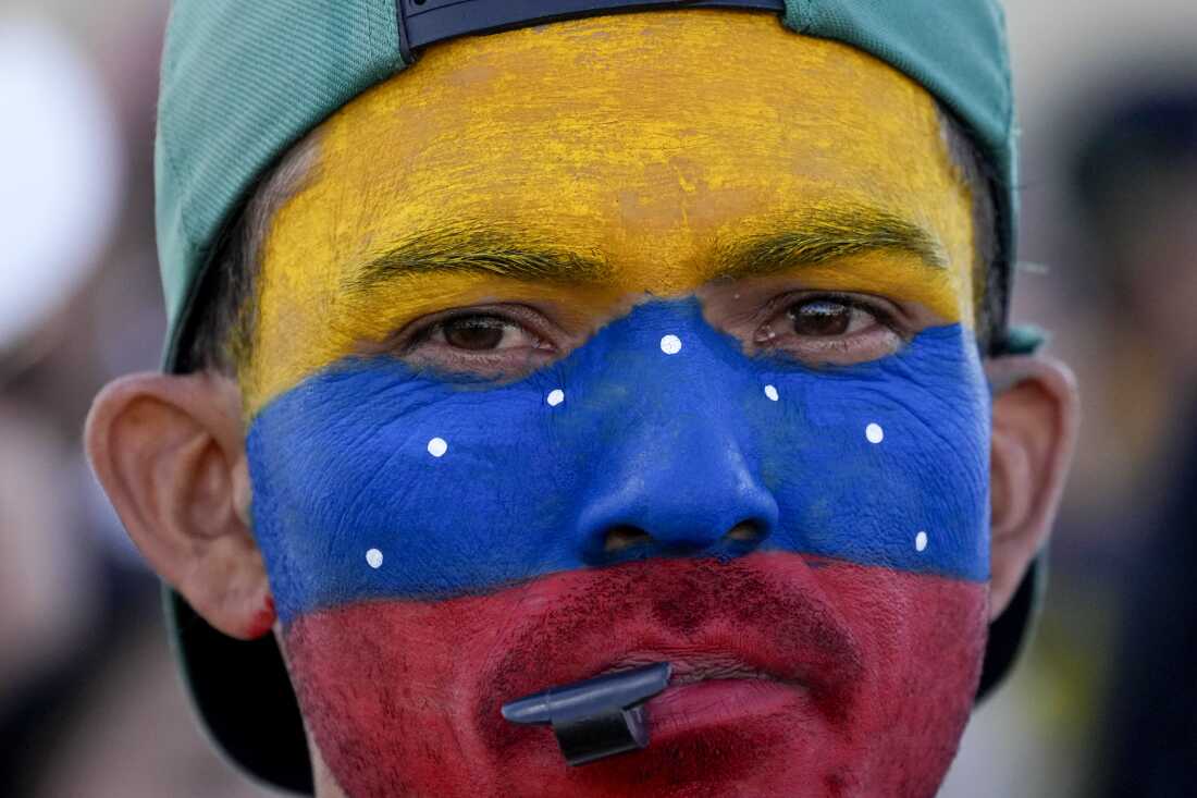 A Venezuelan living in Brasilia, Brazil, with his face painted in the colors of his nation's flag, gathers with fellow Venezuelans on the day of their nation's presidential election, Sunday, July 28, 2024.