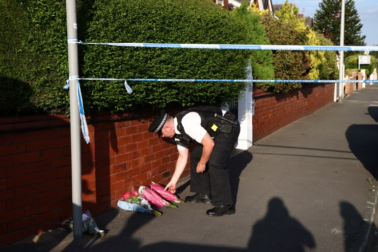 A police officer lays floral tributes brought by wellwishers on Hart Street in Southport, northwest England, on July 29, 2024, following a knife attack