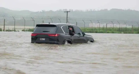 Rodong Sinmun Kim Jong Un in floodwaters.