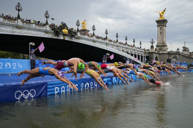 Competitors dive into the Seine River in Paris during the women's Olympic triathlon on July 31. <a href=