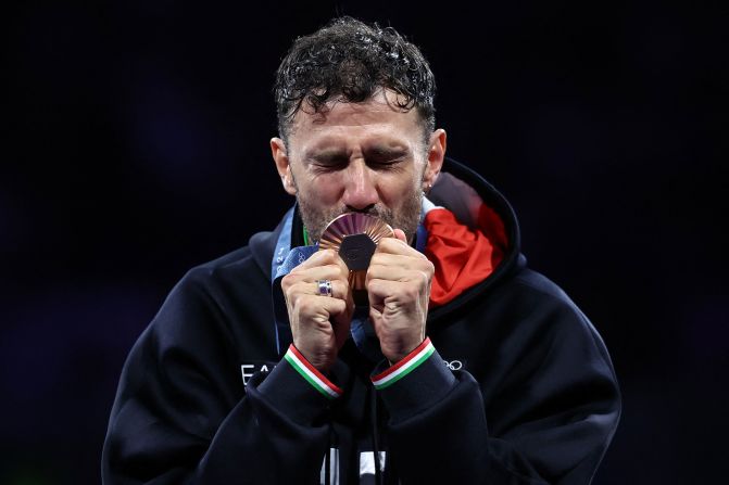 Italian fencer Luigi Samele celebrates on the podium after winning a bronze medal in the individual sabre competition on July 27.