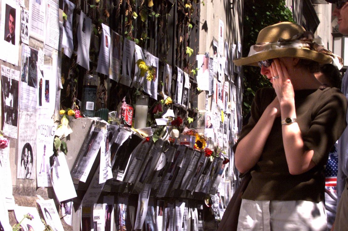 A woman wipes away tears as she views photographs of people missing after the 9/11 terrorist attack, on September 16, 2001. The posters were put up in front of the Armory on 25th Street, which had been converted to a family center for victims of the attack.