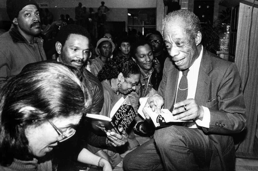 James Baldwin signing books in a crowded book store in 1980.