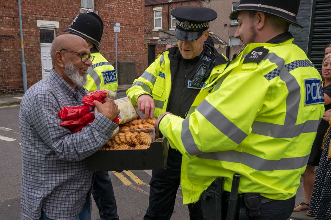 Food and snacks are offered to police officers by local residents as they stand on a police line while far-right activists hold a demonstration in Middlesbrough, England on Sunday.