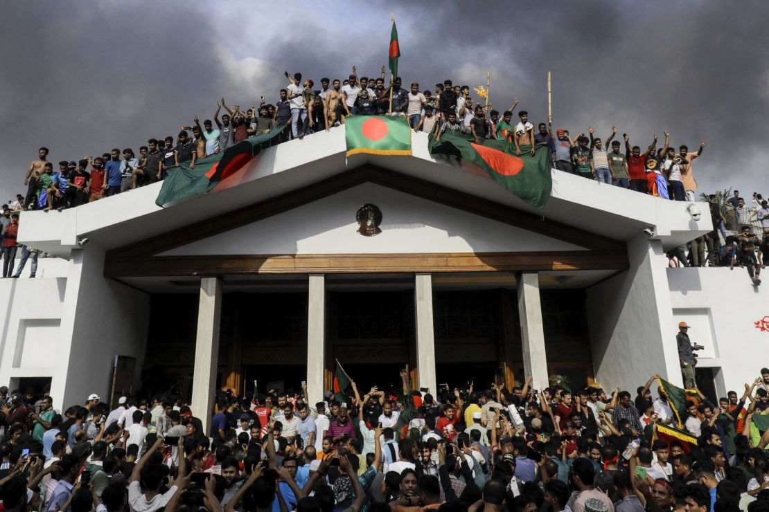 Anti-government protesters display Bangladesh's national flag as they storm Hasina's palace in Dhaka.