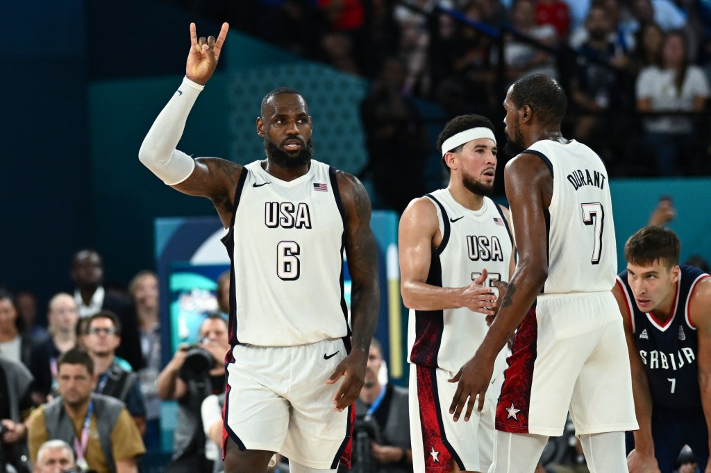 LeBron James, USA's #15 Devin Booker and USA's #07 Kevin Durant celebrate as Serbia's #07 Bogdan Bogdanovic (R) looks on at the end of the men's semifinal basketball match between USA and Serbia during the Paris 2024 Olympic Games at the Bercy  Arena in Paris on August 8, 2024. 