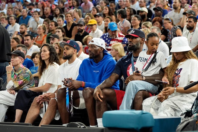 Megan Rapinoe, Sue Bird, Derrick White, Bam Adebayo and LeBron James and his family sit courtside.