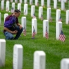 A man places flowers in front of headstones in Section 60, which mark the final resting place of service men and women at Arlington National Cemetery on May 27 in Arlington, Va. Originally known as Decoration Day, Memorial Day began after the Civil War to commemorate soldiers who died in that conflict and now honors all Americans who have sacrificed their lives in all wars. (Photo by Kent Nishimura/Getty Images)