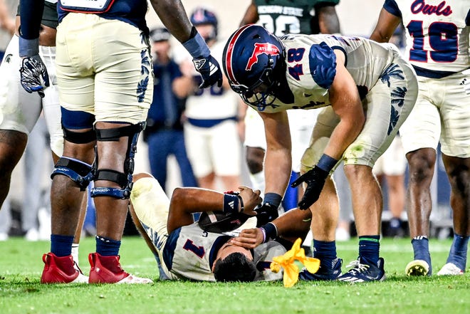 Florida Atlantic's Cam Fancher, below, is slow to get up after getting hit as teammate Charlie Baker checks on him during the fourth quarter in the game against Michigan State on Friday, Aug. 30, 2024, at Spartan Stadium in East Lansing. The penalty on the play was overturned.