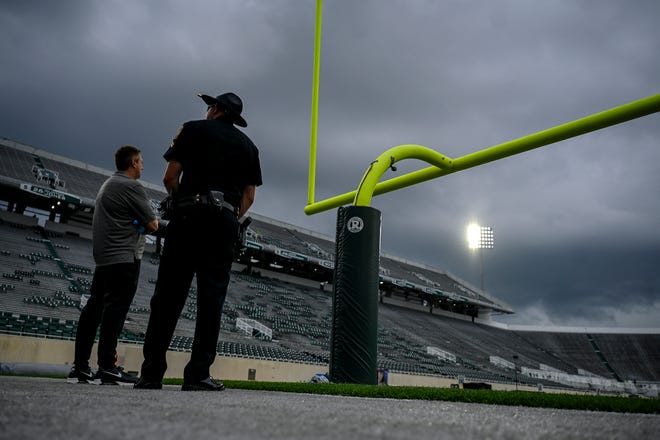 A Florida Atlantic University police officer checks out the sky as a storm rolls in before Michigan State's game against the Owls on Friday, Aug. 30, 2024, at Spartan Stadium in East Lansing. Entry into the stadium was delayed due to weather.