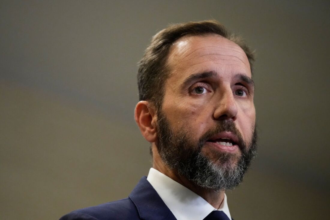 This photo shows special counsel Jack Smith from the shoulders up. He's wearing a dark blue suit jacket and white collared shirt. He has brown hair and a beard.