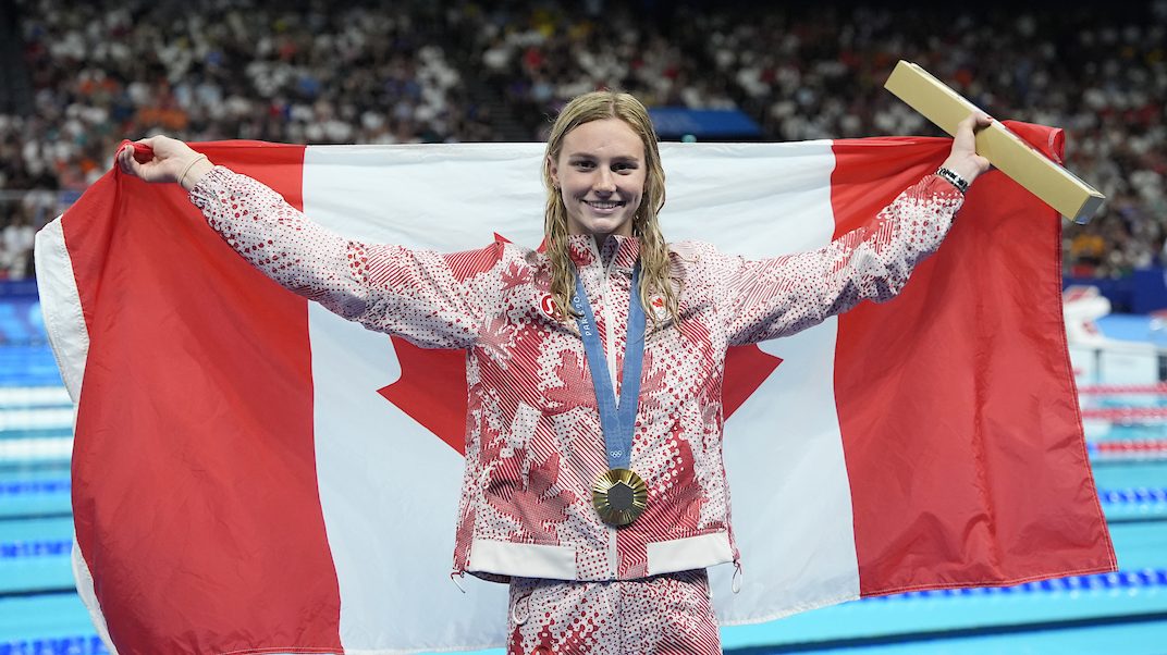 Summer McIntosh poses with a Canadian flag while wearing her gold medal