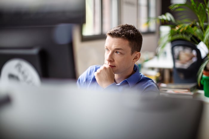 An investor looks pensively at something on a computer.