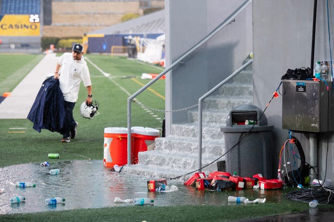 A Penn State personnel member takes equipment out of the rain during a weather delay between Penn State and West Virginia, Saturday, August 31, 2024, in Morgantown, W. Va.