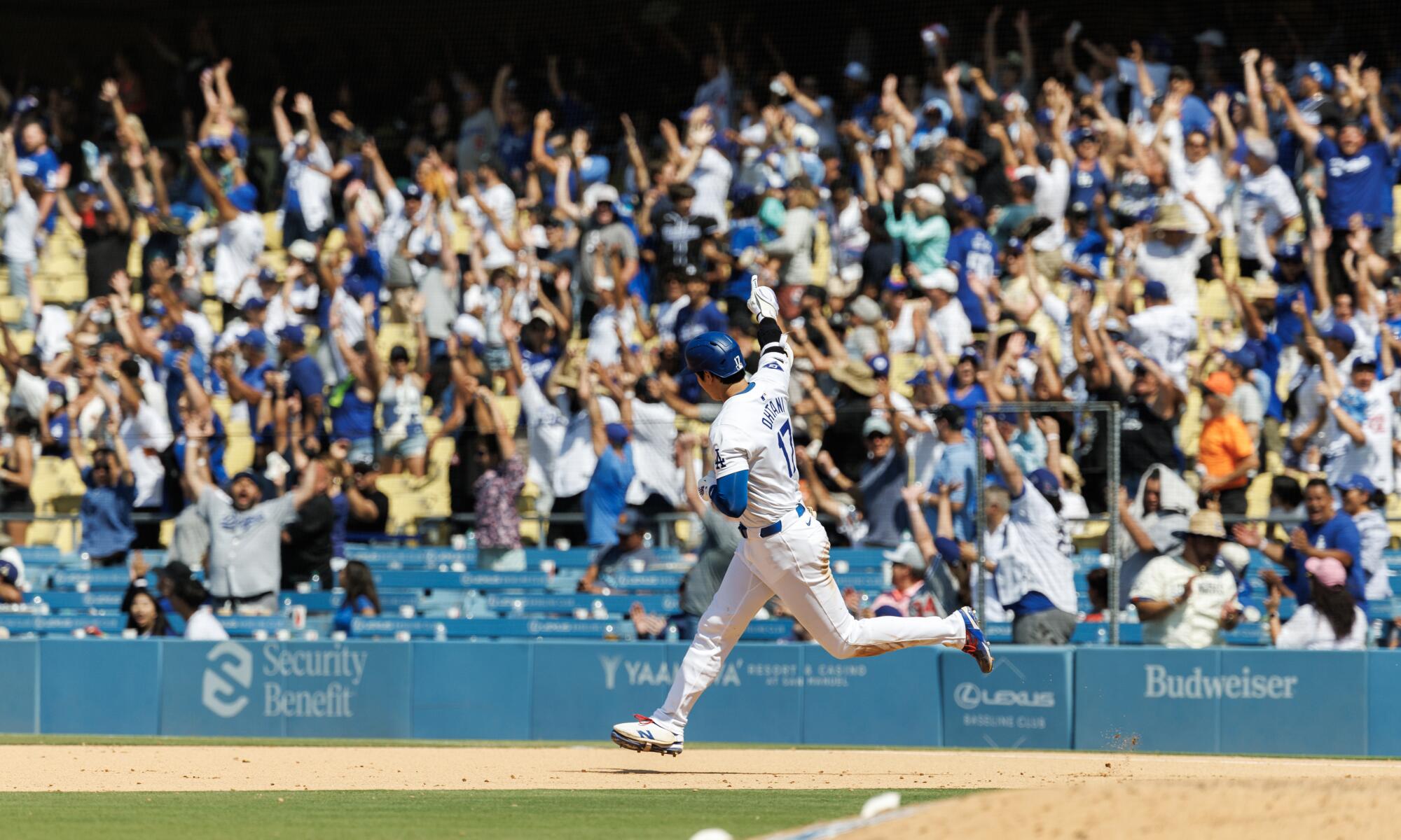 Dodgers fans cheer Shohei Ohtani as he rounds the bases after hitting a solo home run.