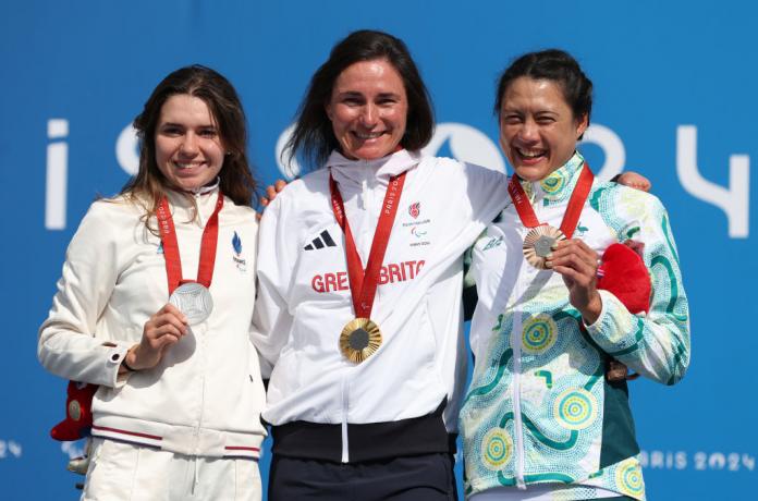 Three women stand on a podium wearing medals