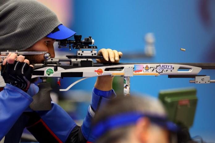 A man with a prosthetic hand takes aim with a shooting Para sport rifle