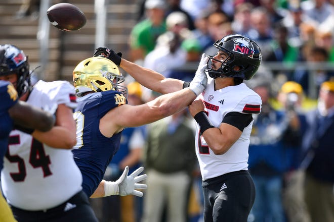 Sep 7, 2024; South Bend, Indiana, USA; Northern Illinois Huskies quarterback Ethan Hampton (2) throws a pass for a touchdown as he is pressured by Notre Dame Fighting Irish defensive lineman Rylie Mills (99) in the first quarter at Notre Dame Stadium. Mandatory Credit: Matt Cashore-Imagn Images