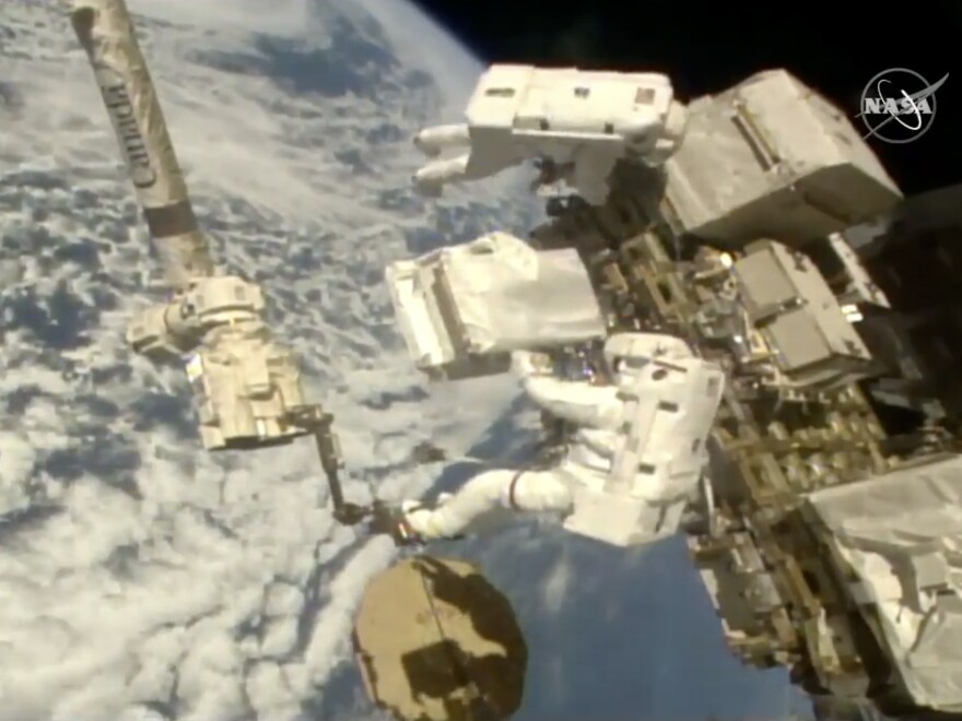 In this image taken from NASA video Italian astronaut Luca Parmitano (lower right) holds a bundle of new pumps for the Alpha Magnetic Spectrometer outside the International Space Station on Dec. 2, 2019. 