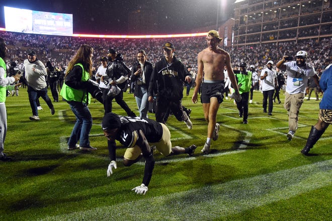 Colorado Buffaloes wide receiver Travis Hunter (12) in the end zone as he is chased by fans trying to leave the field following an overtime win against the Baylor Bears at Folsom Field.