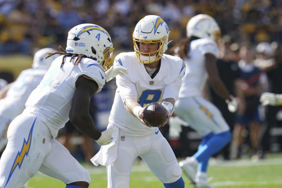 Chargers quarterback Taylor Heinicke hands off the ball to Gus Edwards