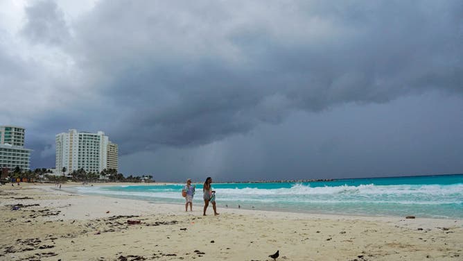 Storm clouds are pictured as people walk on the beach ahead of the arrival of Hurricane Helene in Cancun, Quintana Roo state, Mexico on September 24, 2024.