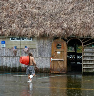 A man carrying a basket walks through floodwaters in Saint Marks, Fla., about 30 miles south of Tallahassee, on Sept. 26, 2024, in advance of Hurricane Helene.