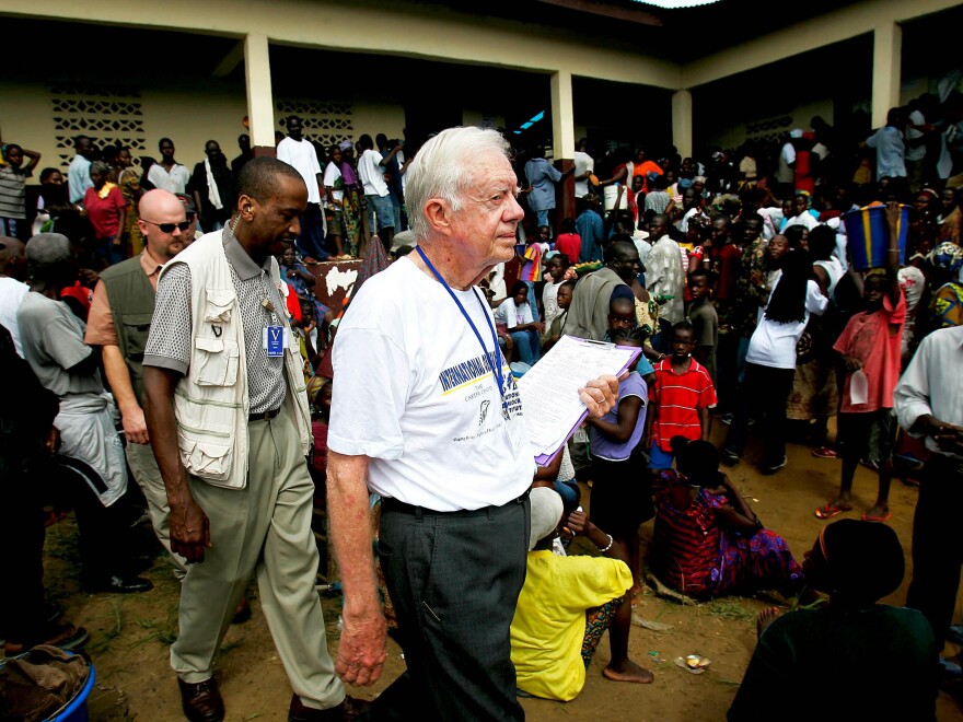 Carter exits a polling site in October 2005 in Monrovia, Liberia. The Carter Center, founded by Carter and his wife Rosalynn Carter in 1982, monitors elections around the world to promote fair and free voting.