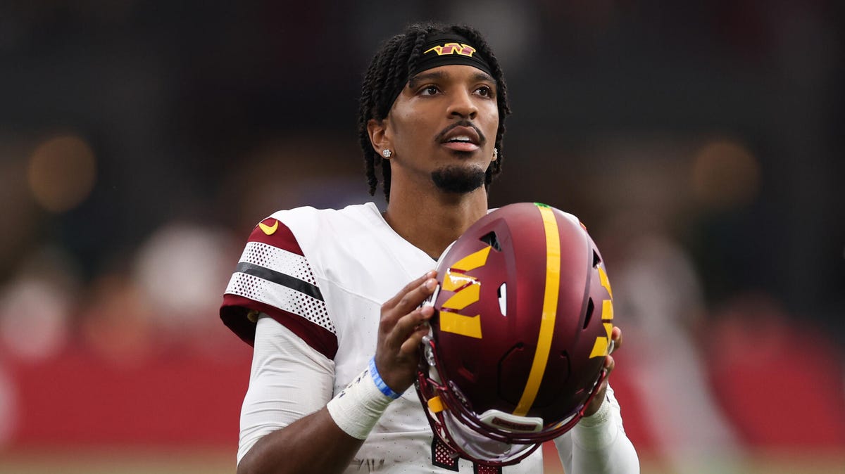 Jayden Daniels of the Washington Commanders holding a helmet with both hands.