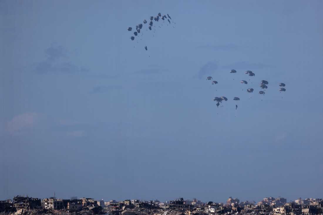 Humanitarian aid falls from planes over northern Gaza as seen from Israel's southern border with the Gaza Strip on March 7.