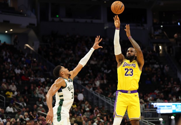 Lakers star LeBron James shoots over Milwaukee Bucks star Giannis...