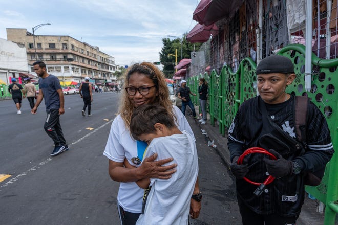 Mari Eduvid Sarmiento holds her son on a street where she works selling clothing. The migrants have lived in Mexico City for months as they await an appointment to seek asylum in the U.S.