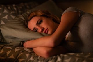 Grace Van Patten as Lucy, lying on a bed with her arms tucked under the pillow, in 'Tell Me Lies' season 2