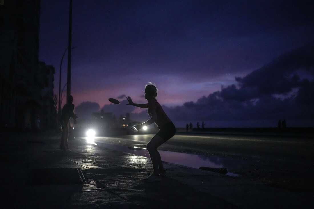 A woman prepares to catch a tossed frisbee during a massive blackout after a major power plant failed in Havana, Cuba, Friday, Oct. 18, 2024.