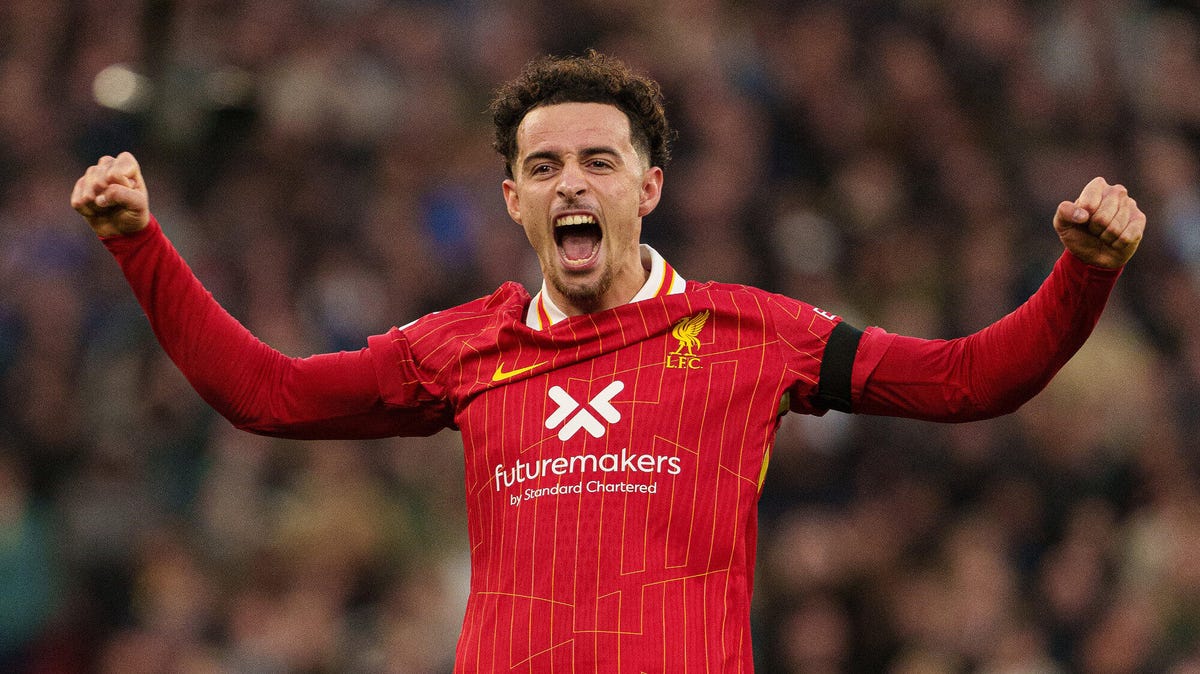 Liverpool's Curtis Jones celebrating with both his arms raised.