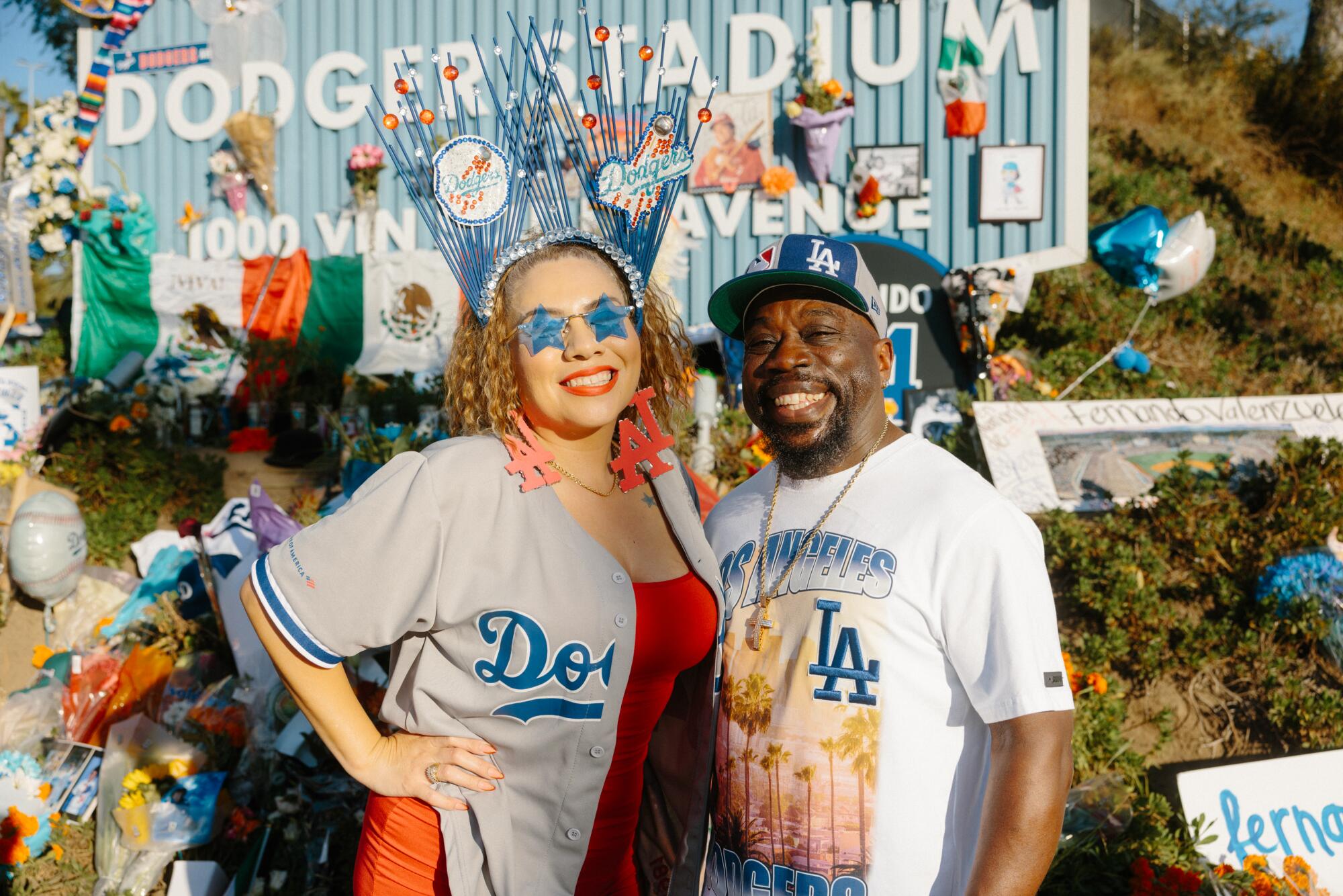  Andre and Margarita Daniels in Dodgers shirts in front of flowers at Dodger Stadium.