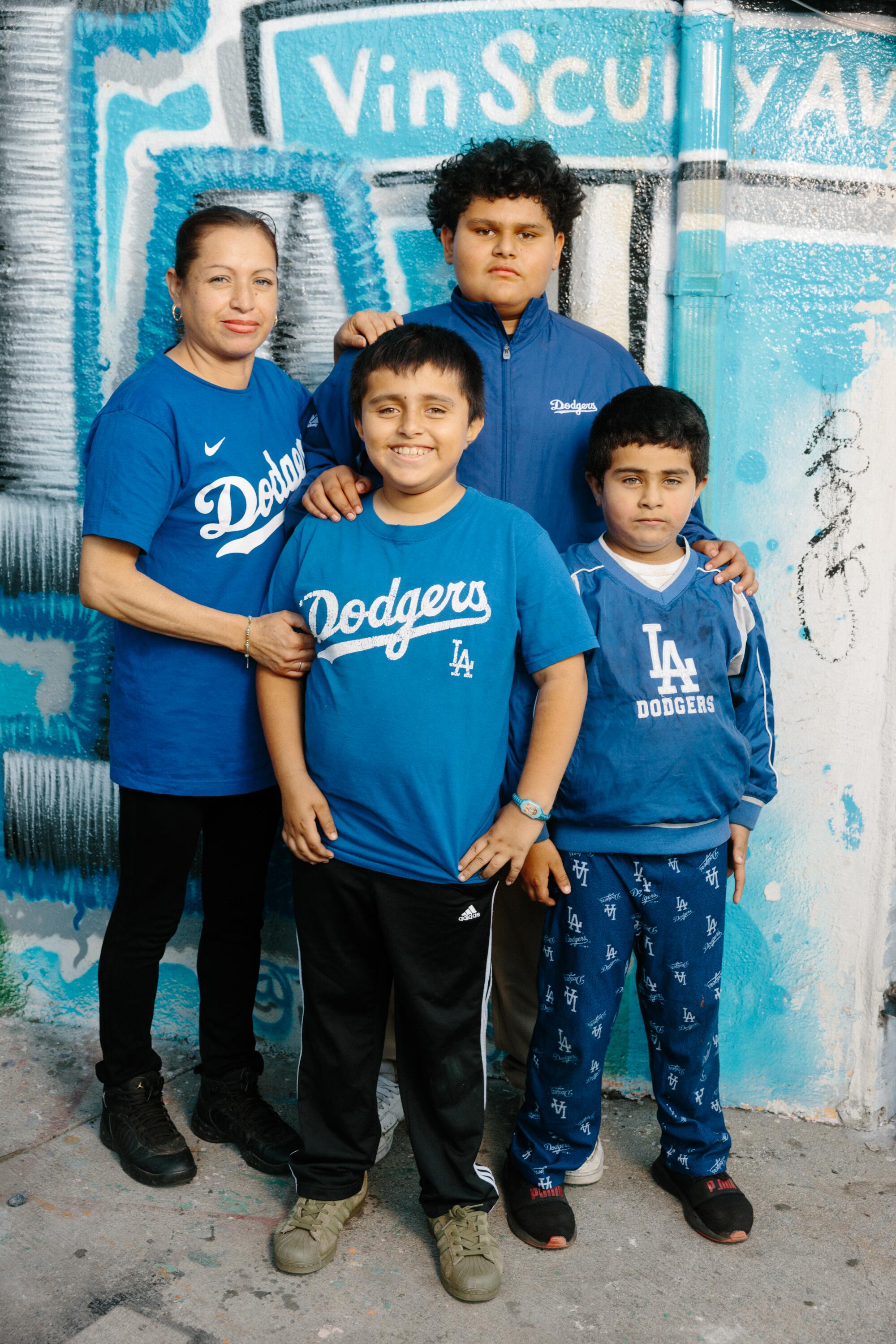 Edilia Morales poses with her sons Raoul Aguilar, Edwin Aguilar, and Allen Aguilar in blue Dodgers shirts.