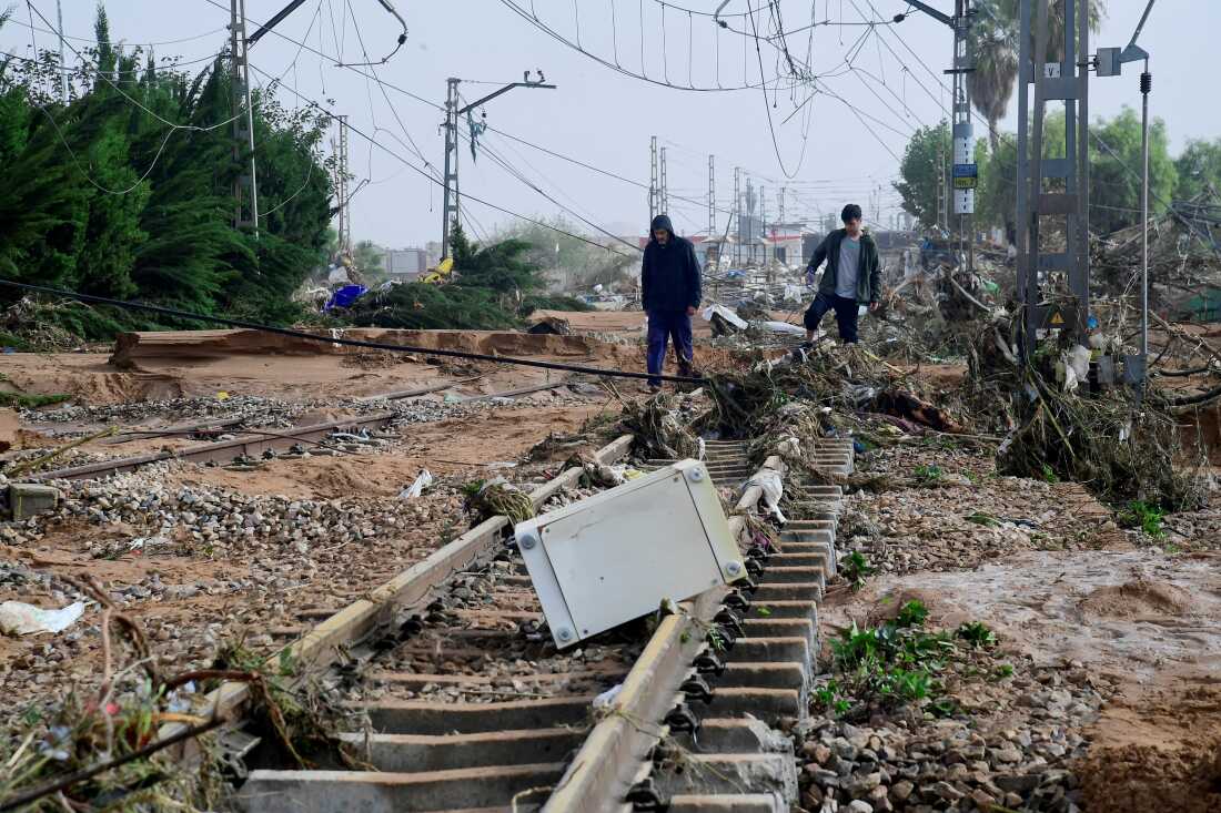 TOPSHOT - Residents walk among debris on a rail track following flood in Picanya, near Valencia, eastern Spain, on October 30, 2024. Floods triggered by torrential rains in Spain's eastern Valencia region has left 51 people dead, rescue services said on October 30. (Photo by Jose Jordan / AFP) (Photo by JOSE JORDAN/AFP via Getty Images)