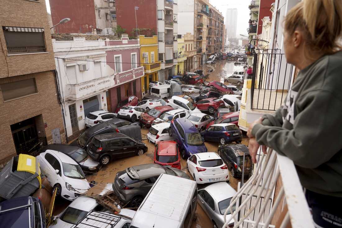 A woman looks out from her balcony as vehicles are trapped in the street during flooding in Valencia, Wednesday.