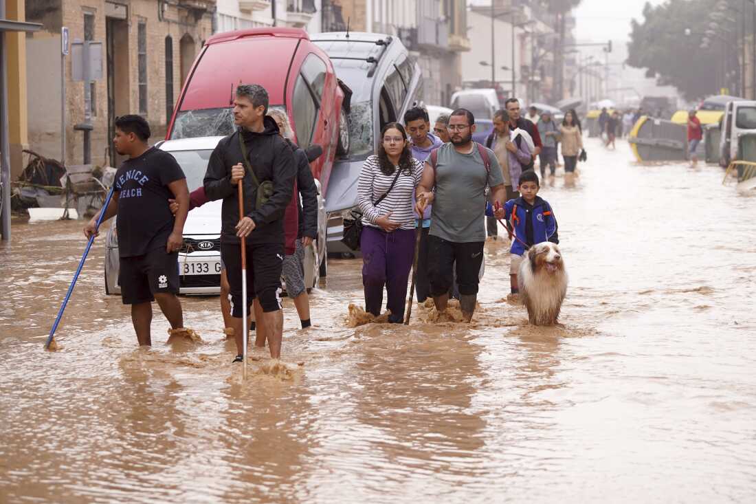 People walk through flooded streets in Valencia, Spain, Wednesday, Oct. 30, 2024. (AP Photo/Alberto Saiz)