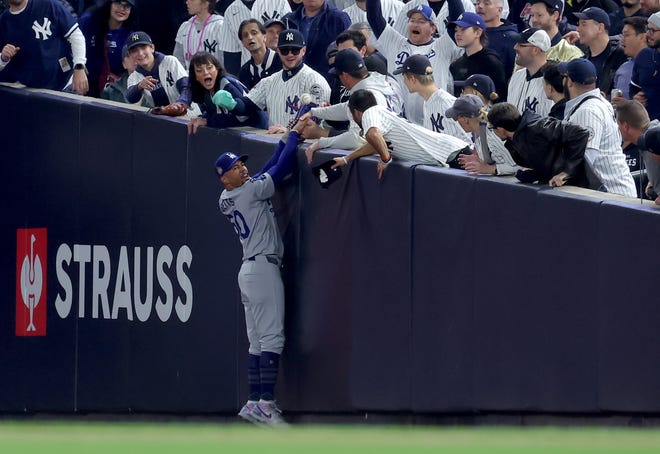 Oct 29, 2024; New York, New York, USA; Los Angeles Dodgers shortstop Mookie Betts (50) makes a catch in foul territory as a New York Yankees fan interferes during the first inning in game four of the 2024 MLB World Series at Yankee Stadium. Mandatory Credit: Brad Penner-Imagn Images