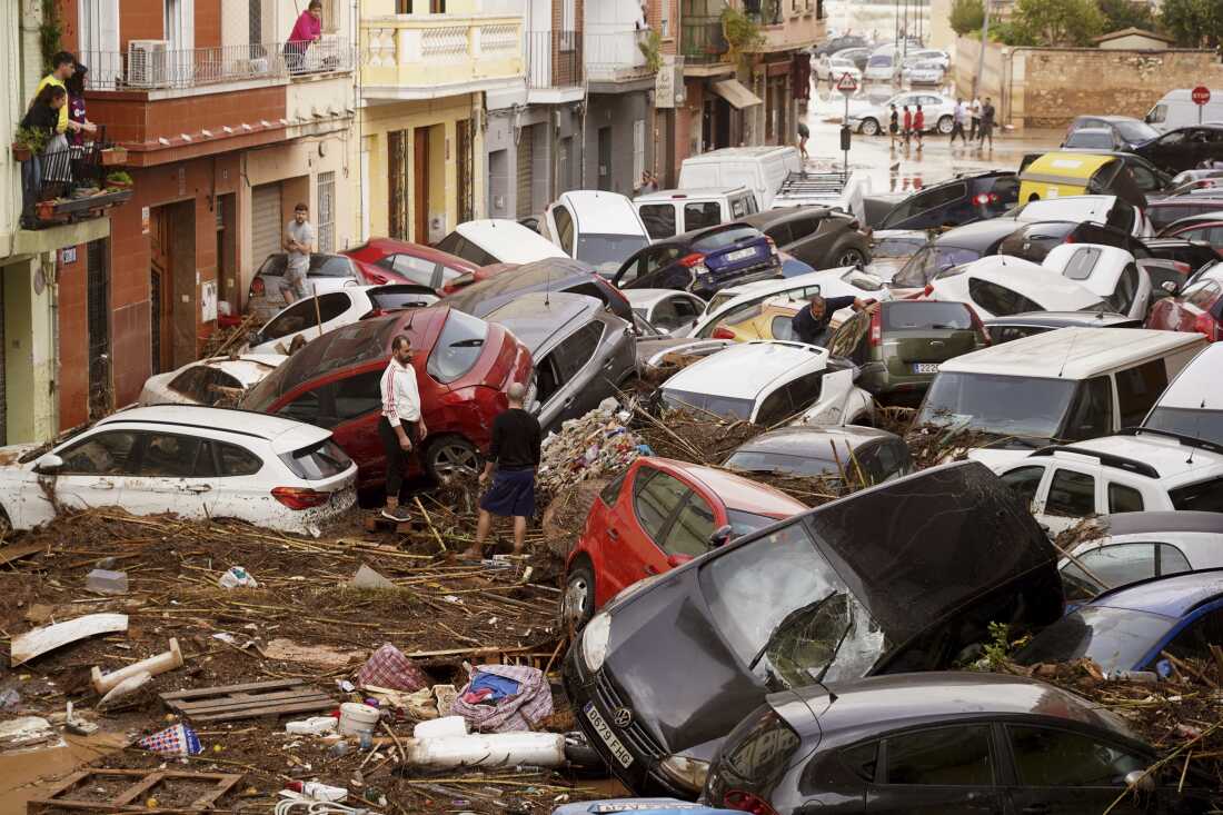 Residents look at cars piled up after being swept away by floods in Valencia, Spain on Wednesday.