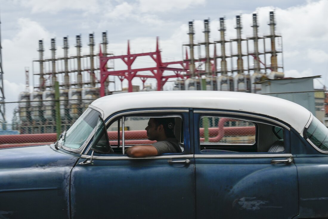 A person drives a classic American car past a floating generator that has not been producing electricity for days in Havana, Cuba, Friday, Oct. 18, 2024.