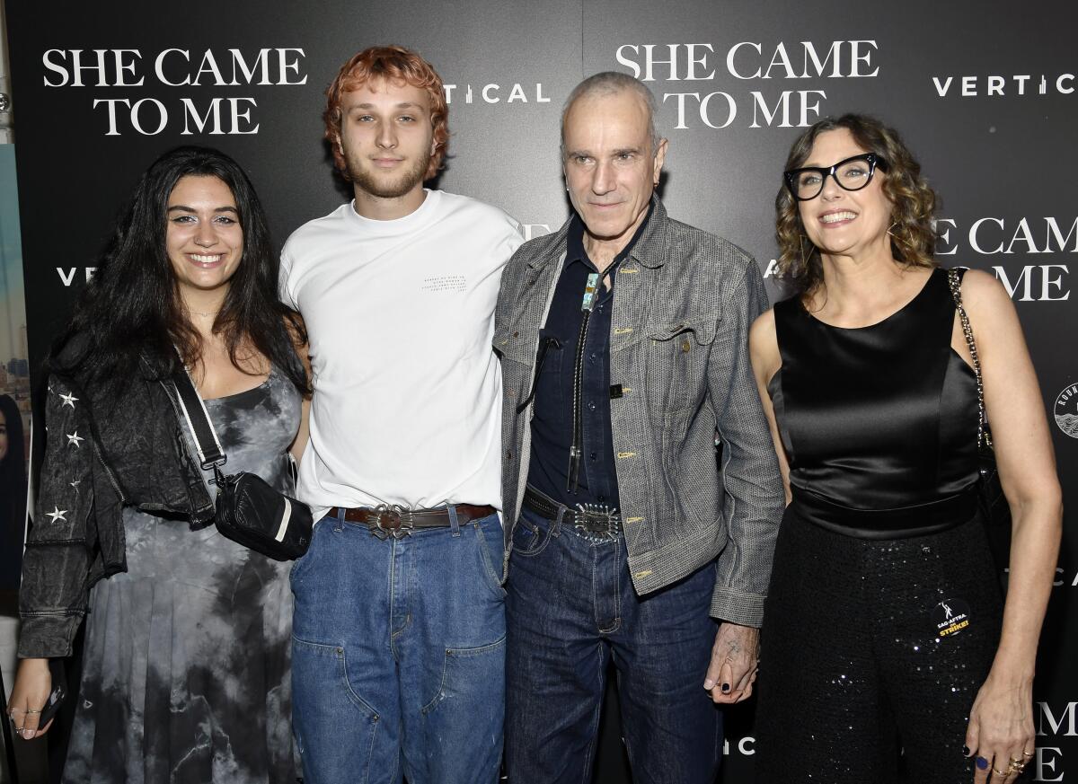 Two men flanked by two women all standing together in a line wearing casual attire at an event